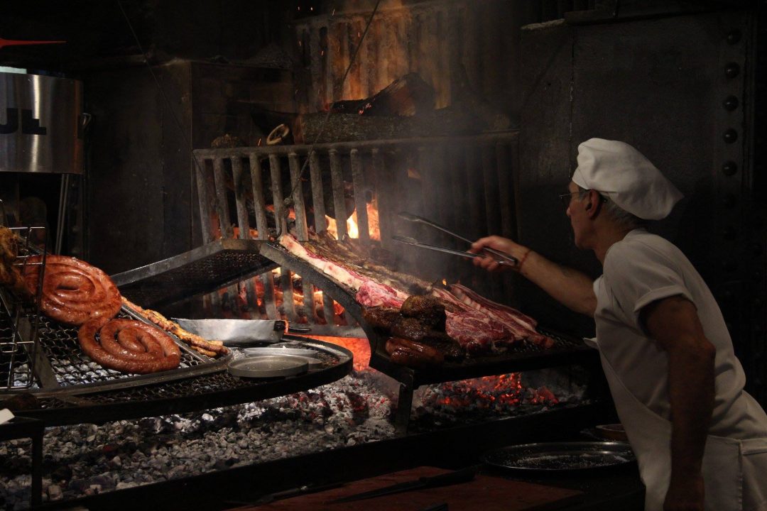 asador moviendo la carne sobre una parrilla tradiciones uruguayas