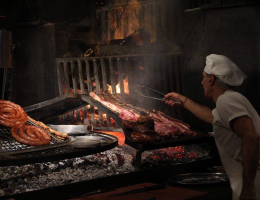 asador moviendo la carne sobre una parrilla tradiciones uruguayas