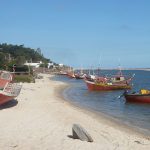 Pequeños botes de pescadores de color rojo atracados en la orilla del Arroyo Pando. Uno de los bote está en la arena