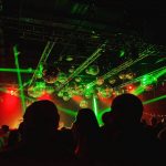 Haces de luces rojas y verdes sobre bolas de espejo en una discoteca repleta de gente bailando